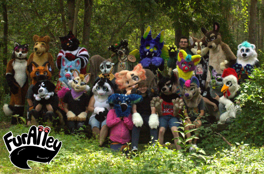 FurAlley group photo with a bunch of fursuiters in a bush. The FurAlley logo is in the bottom left corner.